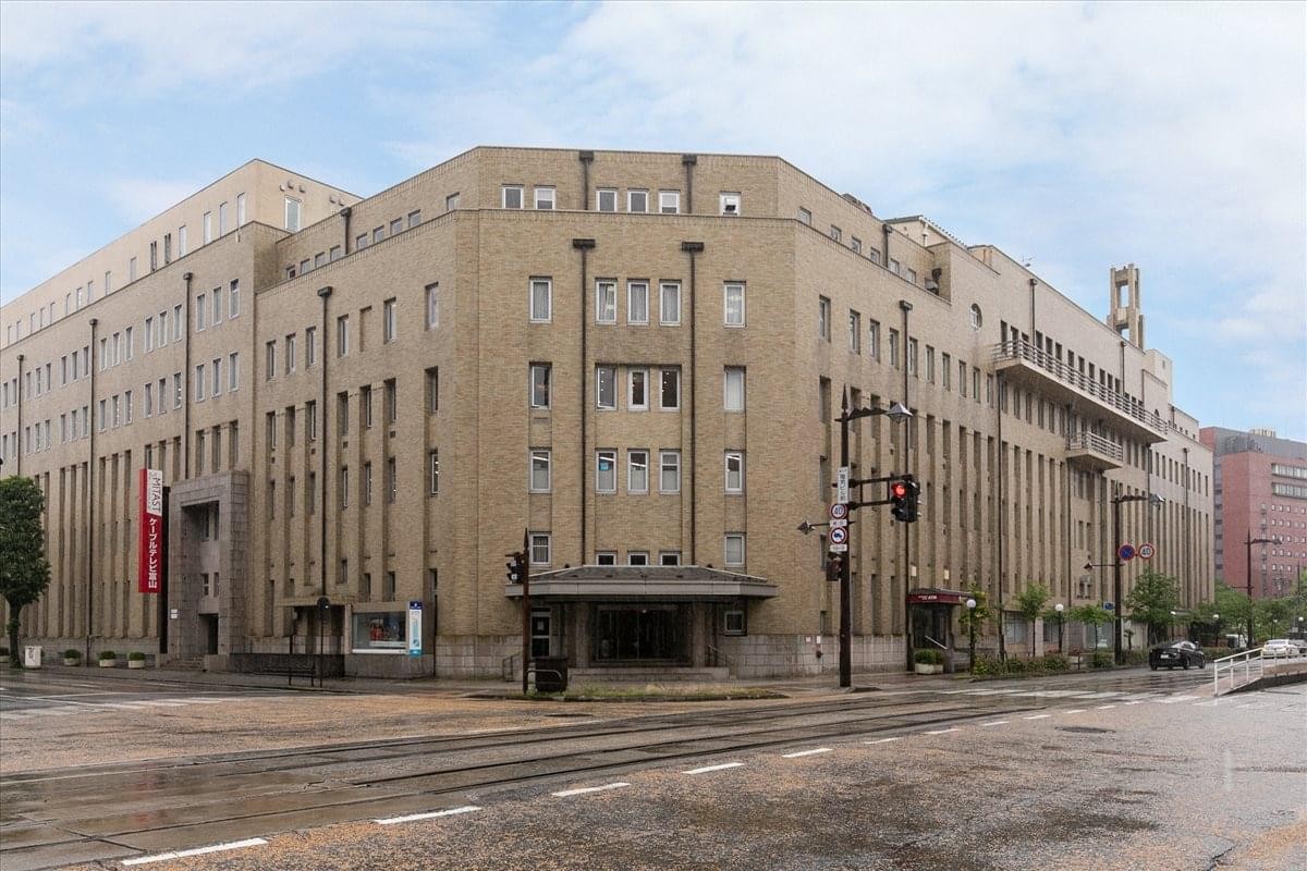 Exterior view of the historic stone-clad Denki Building Honkan with its unique corner entrance.