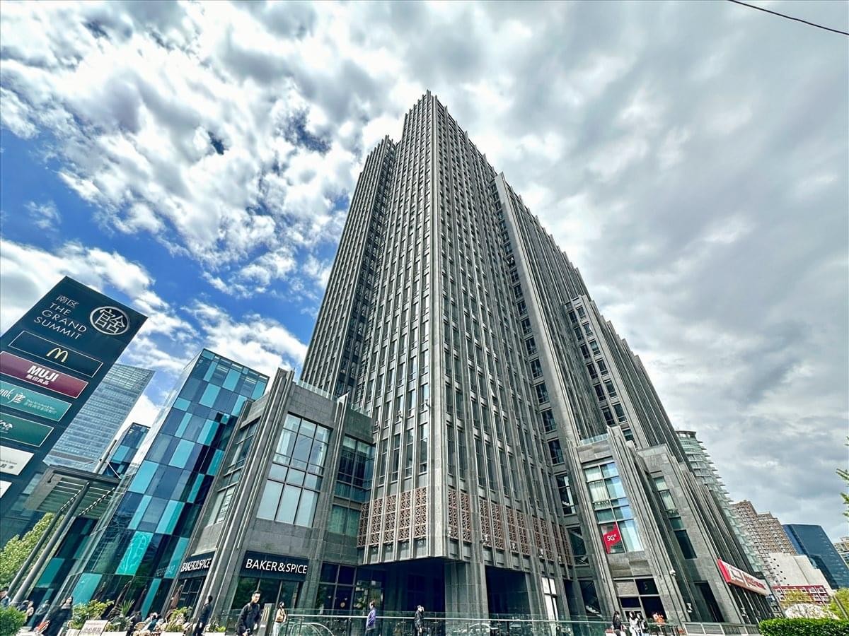 The tall facade of the Liangmaqiao Diplomatic Office Building towers over a glass atrium.
