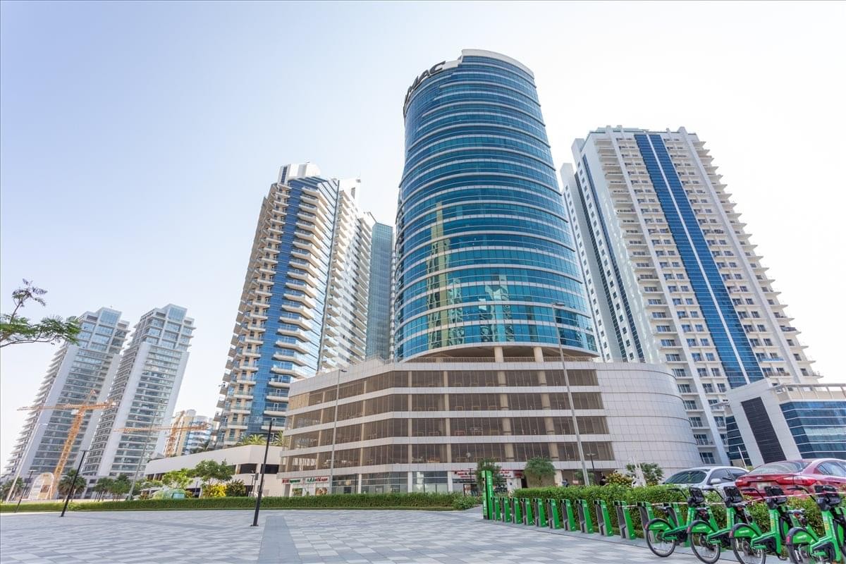 Exterior view of the glass-facade Damac Heights Building against a clear sky.