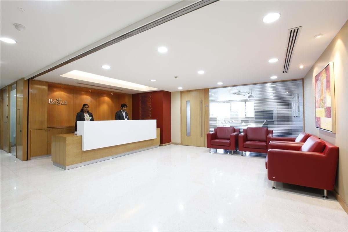 Bright reception area at Dynasty, Andheri-Kurla Road with white desk and red leather seating.
