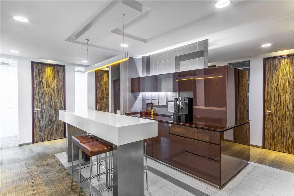 Modern office pantry and break area with a white marble-topped island and sleek dark cabinetry.