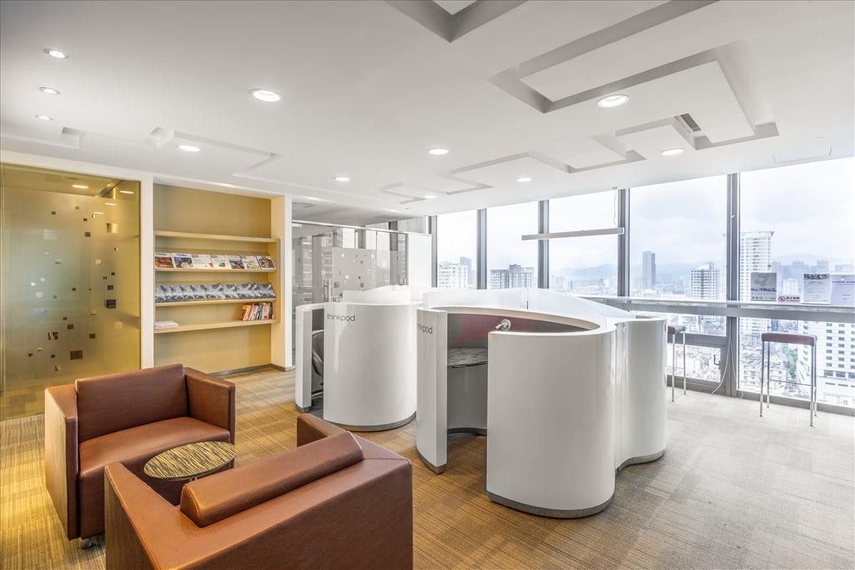 Bright coworking area with white circular pods and expansive city views through floor-to-ceiling windows.