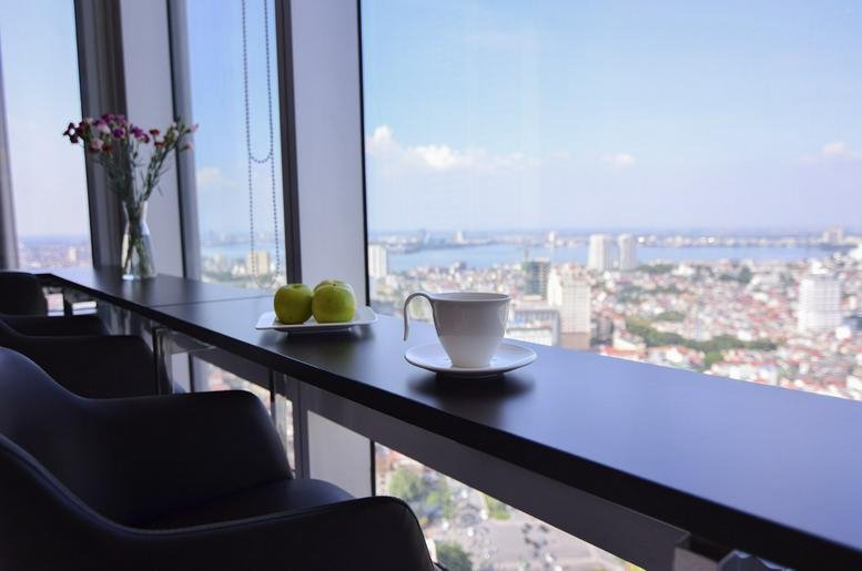 High-altitude window counter with seating, coffee, and a panoramic view of the city.