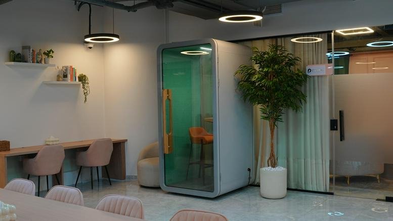 Interior view of the modern Latifa Tower office featuring a sleek phone booth and indoor plants.