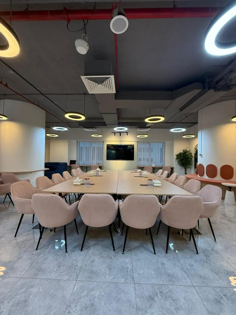 Wide-angle view of a large boardroom at Latifa Tower featuring pink velvet chairs and ring lighting.
