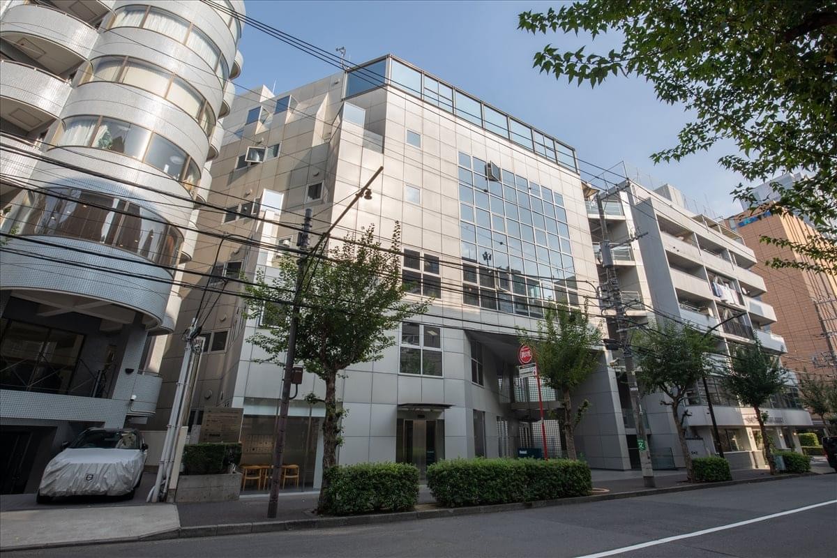 Exterior view of the multi-story 4F Dai 21 Arai Building with a modern glass and stone facade.