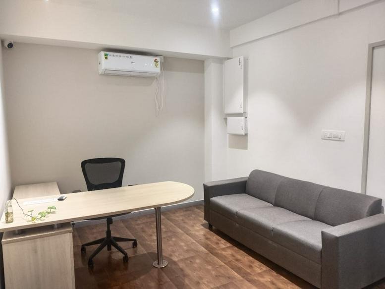 Private office at Eleanor Technologies, Sector 4, HSR Layout, featuring a desk and a grey sofa.