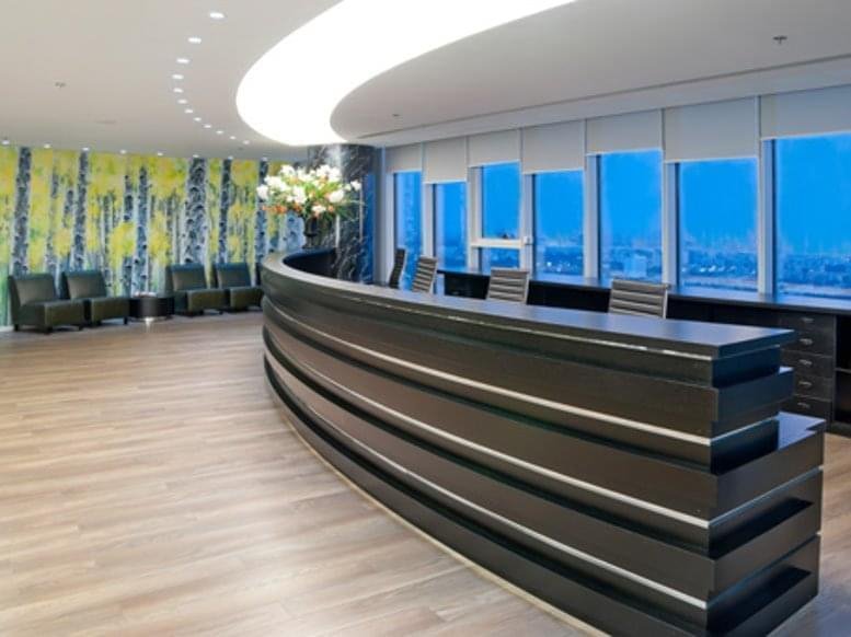 Spacious reception area with a long curved desk and a vibrant tree-patterned feature wall.
