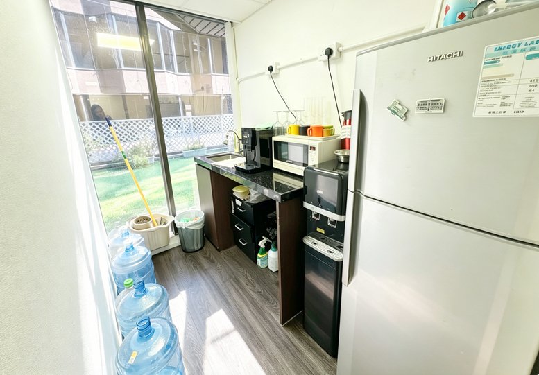 Compact office pantry with a microwave, coffee machine, and refrigerator next to a large window.