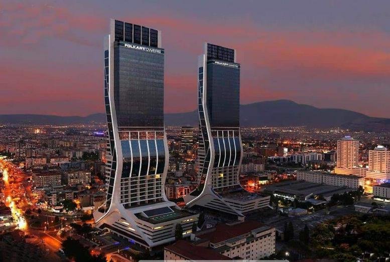 Exterior view of the modern, curved twin skyscrapers of Folkart Towers A Kule at sunset.