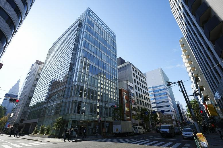 Modern glass-facade exterior of Forcast-Shinjuku AVENUE at a street corner.