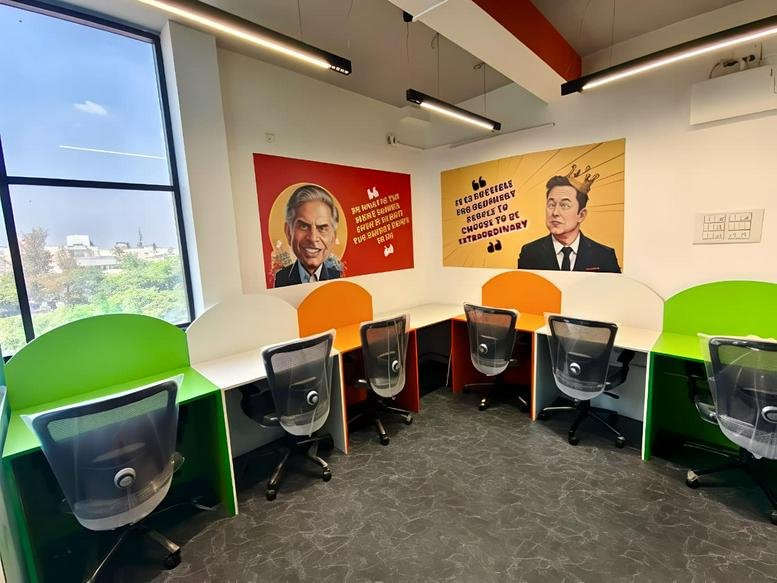 Colorful coworking area with green and orange desks under bright LED lighting.
