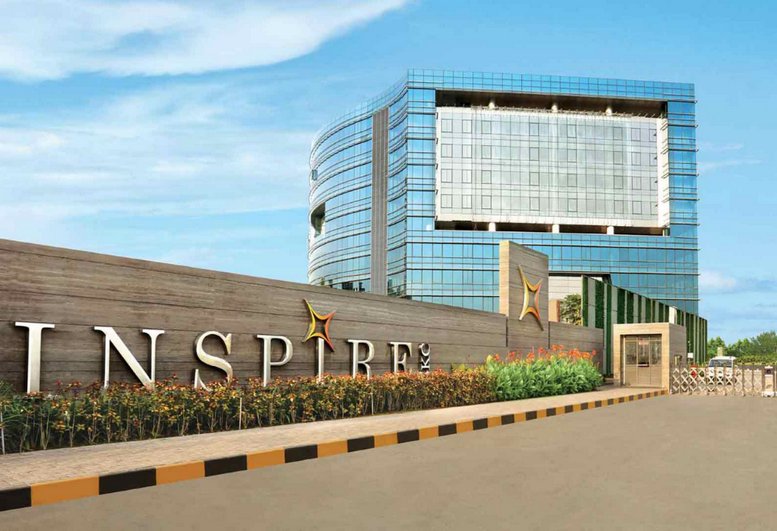 Exterior view of the modern glass facade and entrance signage of Adani Inspire.