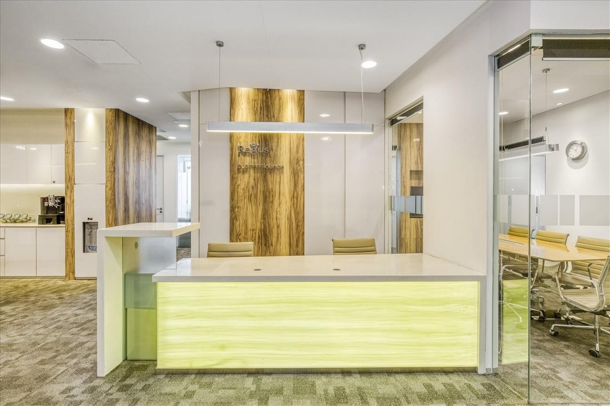 Bright reception area featuring a light wood desk and glass-walled meeting rooms.