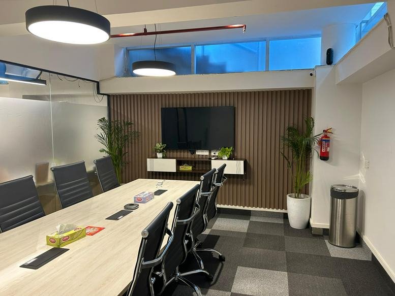 Meeting room at GC Towers with wood-paneled walls, large monitor, and potted plants.