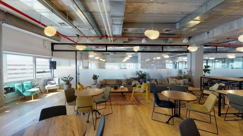 Spacious communal lounge at Gev Yam Negev Park with colorful seating and industrial ceilings.