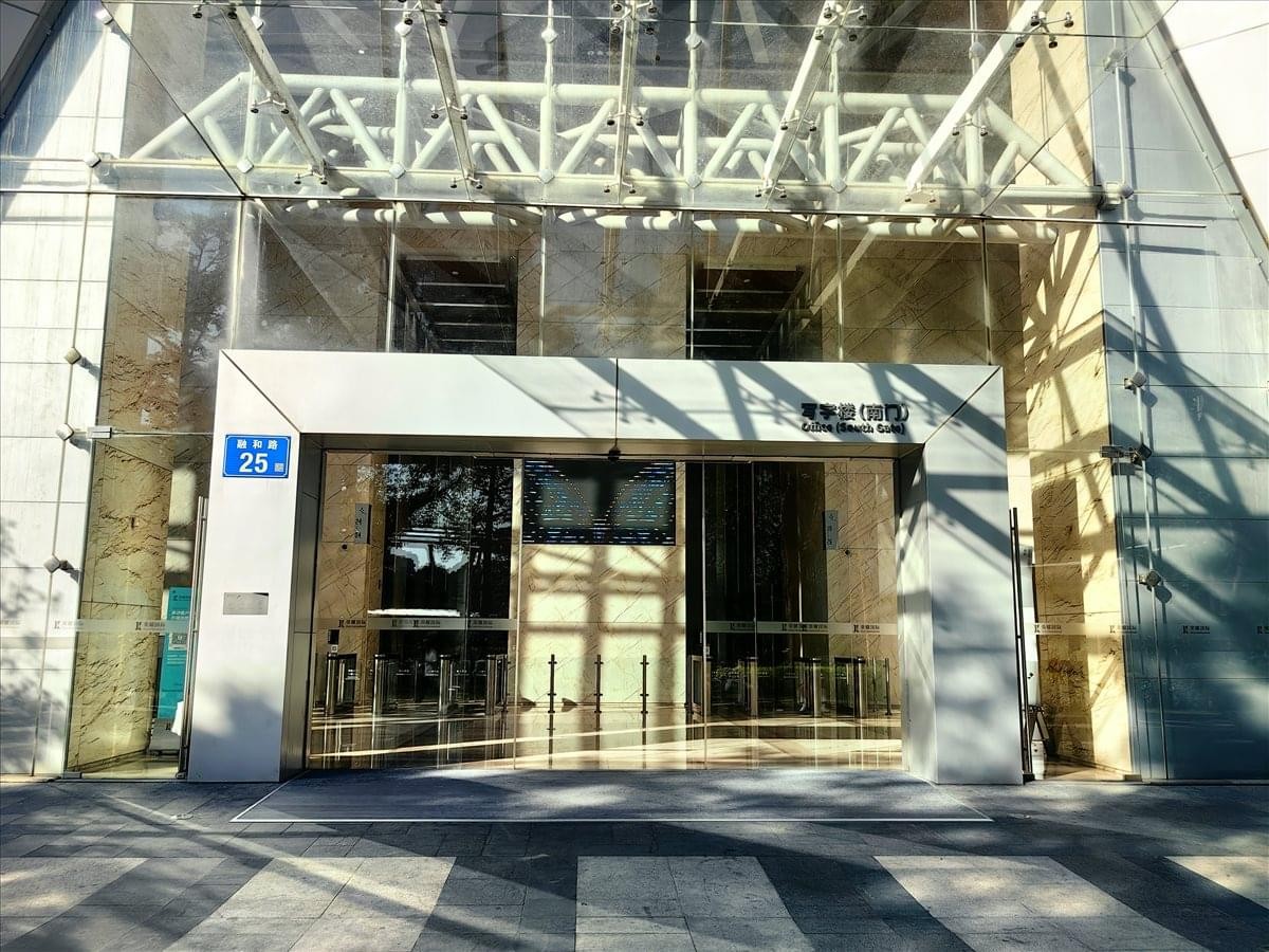Entrance of the Glory IFC building at No. 25 Ronghe Road featuring glass doors and a steel canopy.