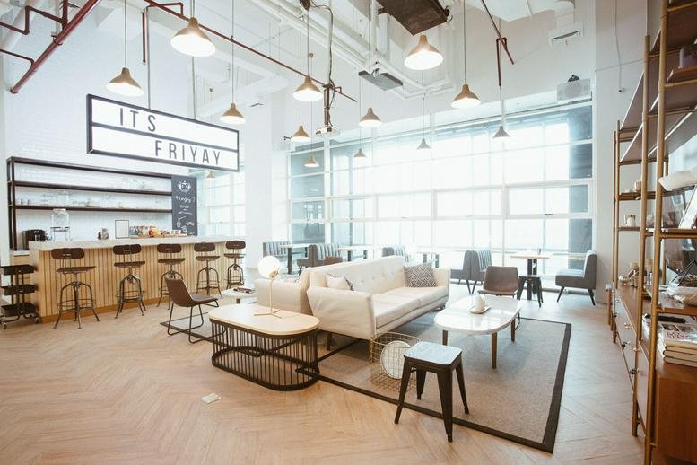 Spacious coworking lounge at GoWork Thamrin, Chubb Square with a bar area, white sofas, and ample natural light.