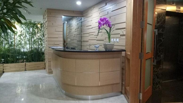 Wooden reception desk at Graha Surveyor Indonesia featuring a purple orchid and bamboo wall.
