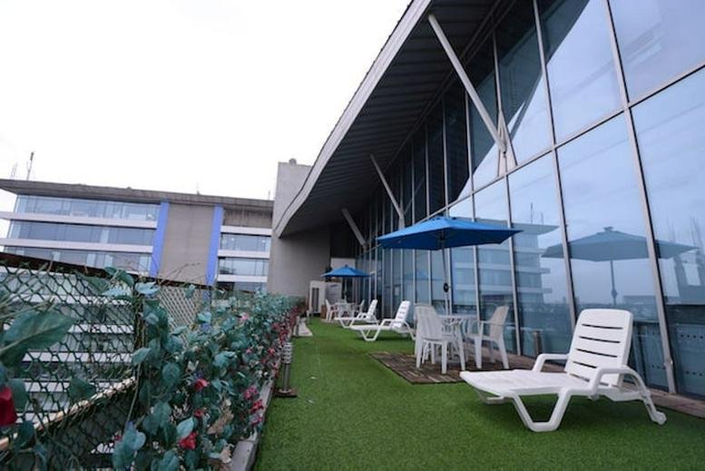 Exterior view of the modern Grande Palladium building featuring a rooftop lounge area with lawn.