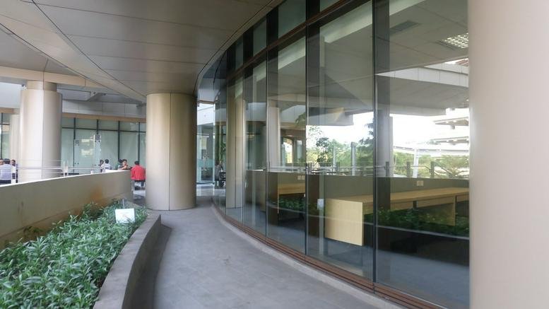 The glass-facade exterior of Green Office Park, MyRepublic Plaza Wing, A showing the curved walkway.