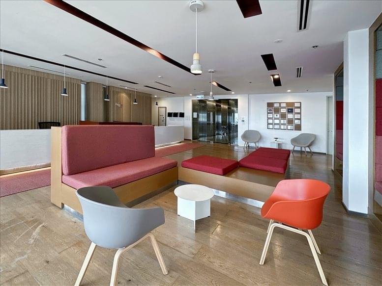 Modern lounge with red cushioned benches, a white coffee table, and orange chairs.