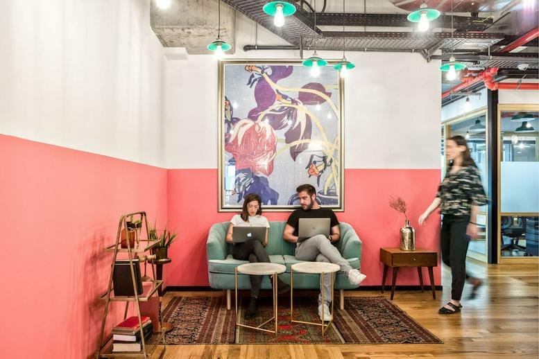 Lounge area with a teal sofa, pink accent wall, and colorful abstract art.