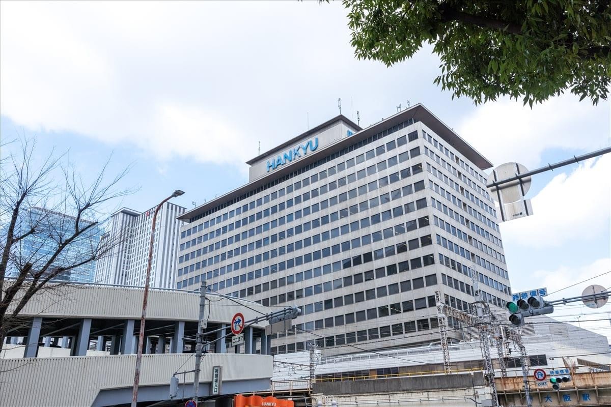 Exterior view of the multi-story Hankyu Terminal Building under a bright sky.