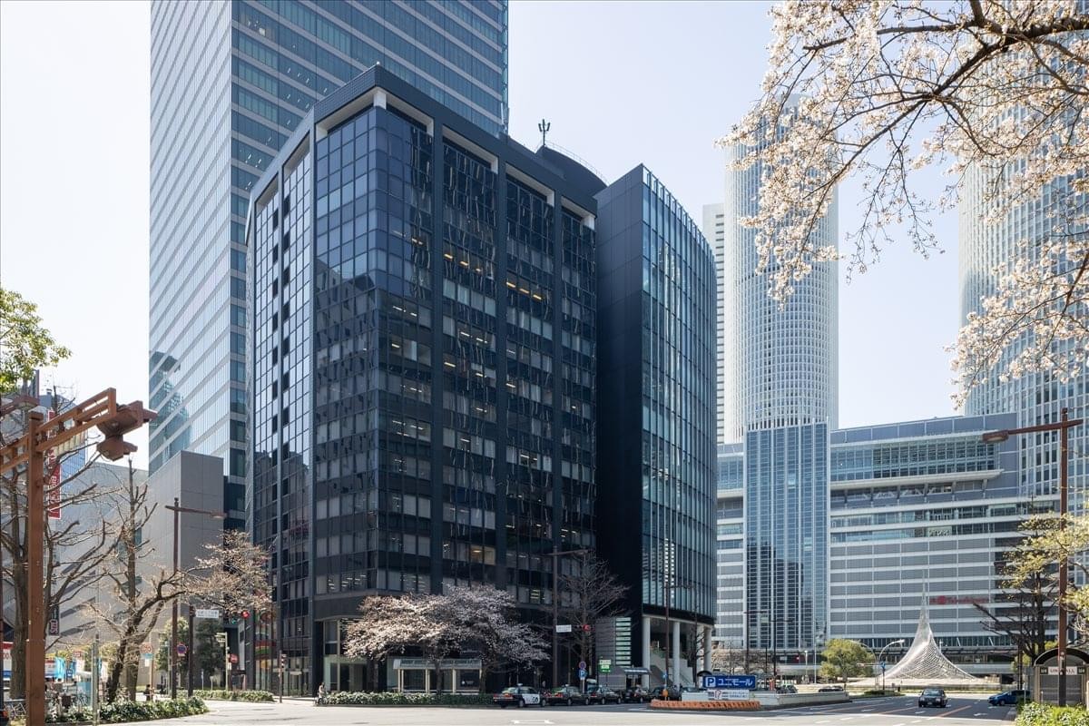 Modern exterior view of Hirokoji Garden Avenue featuring dark glass architecture and cherry blossoms.