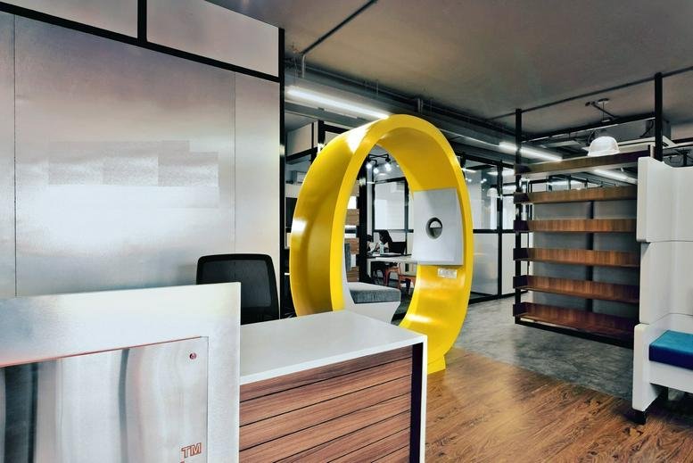 Modern reception area of HM Vibha Towers with a yellow circular feature and wooden desk.