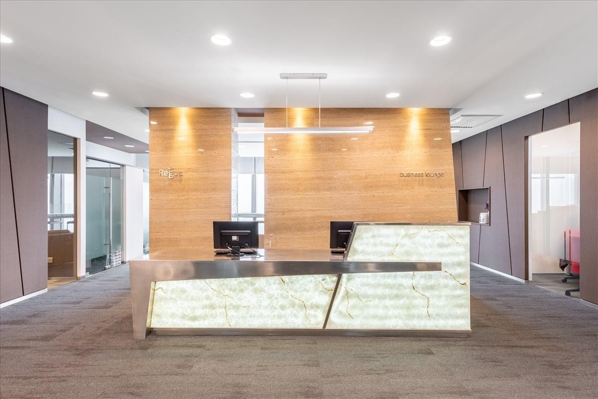 Bright reception desk featuring a backlit stone textured front and wood paneling.