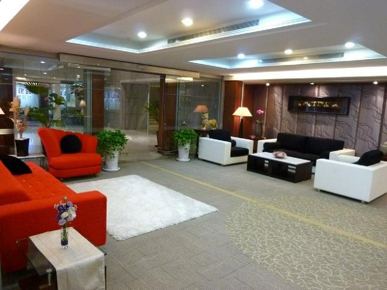 Spacious communal lounge featuring vibrant orange sofas, white armchairs, and indoor plants.