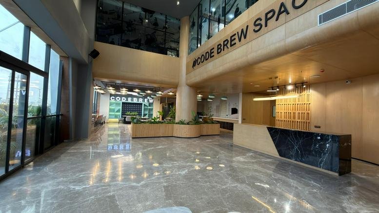 Wide-angle view of the modern reception lobby at Code Brew with a dark marble desk.