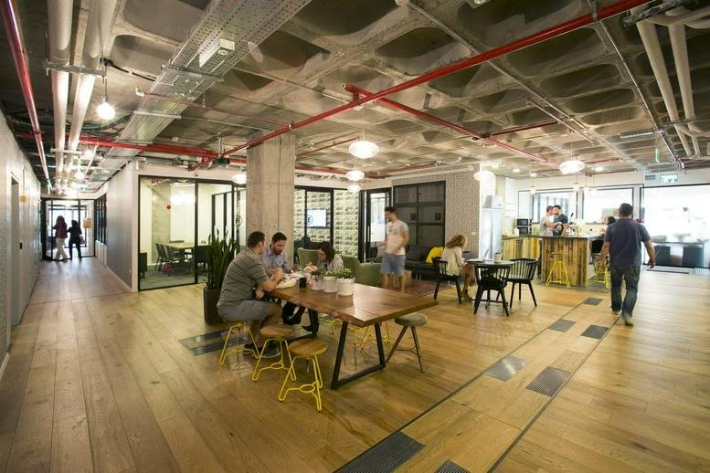 Spacious communal coworking lounge at Ibn Gabirol 30, Tel Aviv, Israel with wooden floors and industrial ceilings.