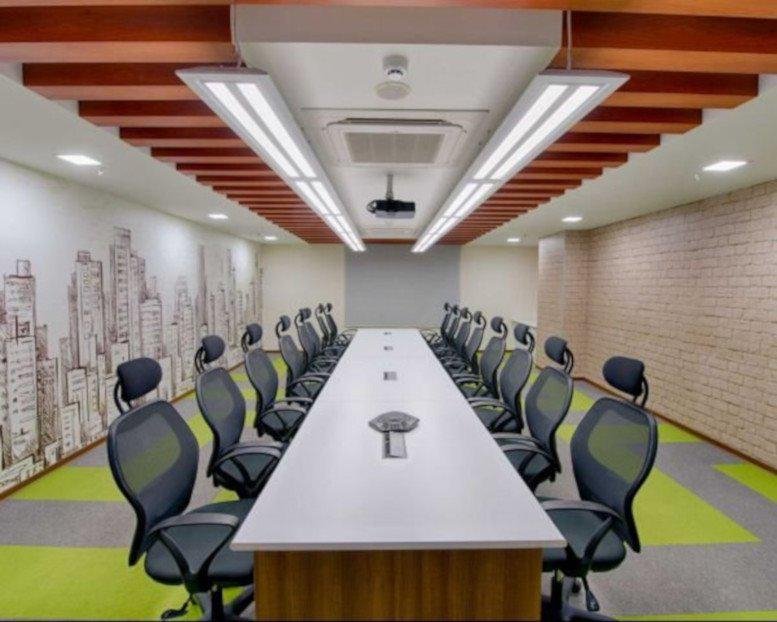 Meeting room at IndiQube Edge with a long white table, ergonomic chairs, and city skyline wall art.