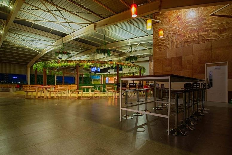 Spacious communal lounge at Indiqube Summer Court with warm lighting and decorative greenery.