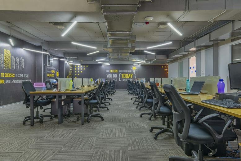 Spacious open-plan workspace at Indiqube Townhub with rows of ergonomic chairs and modern overhead lighting.