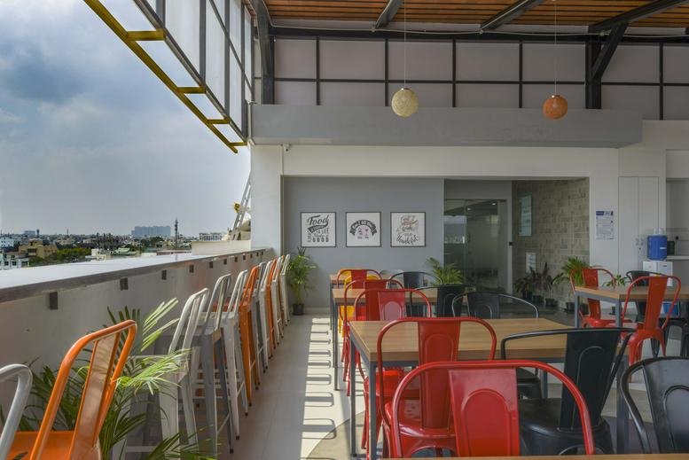 Outdoor seating area with colorful metal chairs and city view.