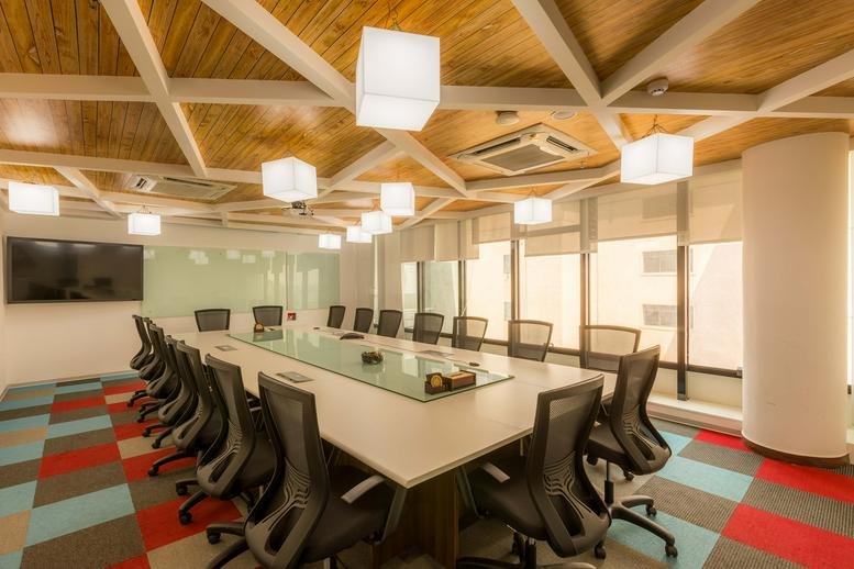 Spacious boardroom at Indiqube Zeta, Bren Mercury, Sarjapur Main Road, with a glass table and geometric wood ceiling.