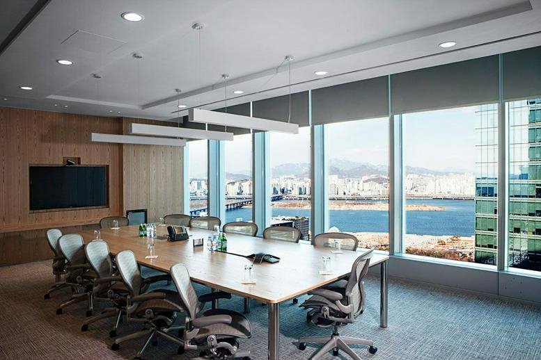 Large boardroom with floor-to-ceiling windows offering expansive city and river views.