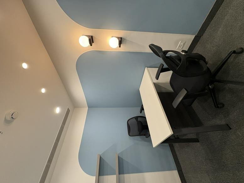 Single workstation pod in Ithum Tower A featuring blue arched wall accents and warm pendant lighting.