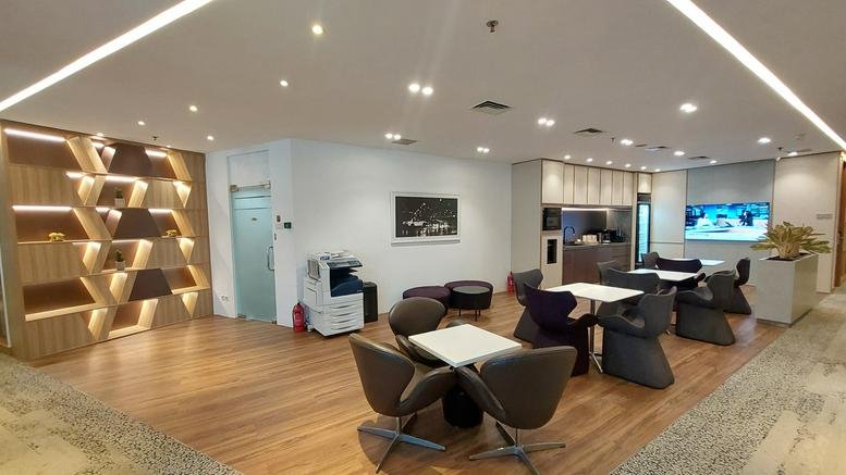 Spacious communal lounge with modern seating, wooden floors, and a feature bookshelf wall.