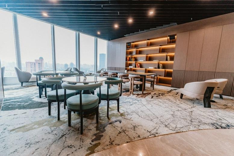 Spacious lounge with diverse seating, bookshelves, and city views at Jing'an Kerry Centre Tower 3.
