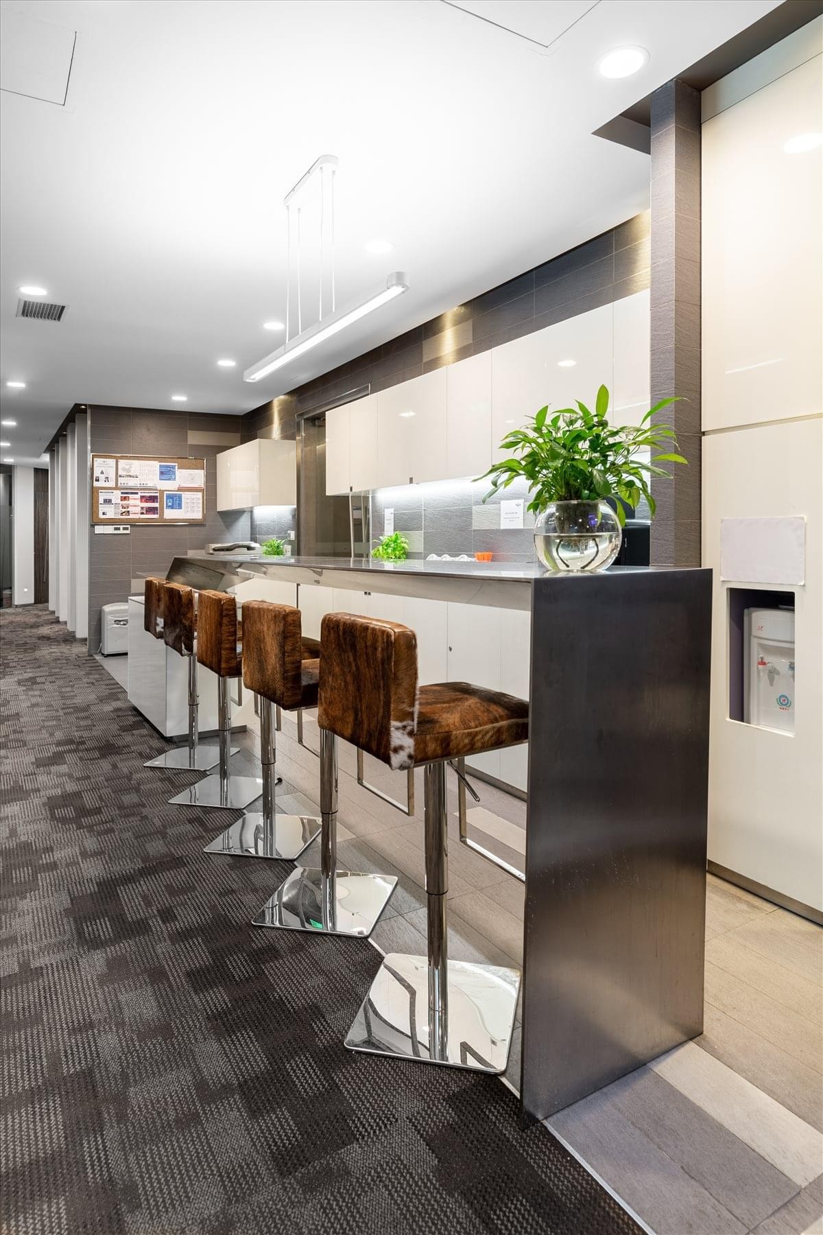 Modern breakout kitchen and bar area featuring cowhide-textured stools and a sleek grey counter.