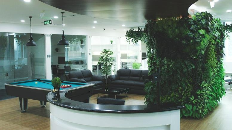 Spacious communal area at The City Center with pool table, leather sofas, and a lush vertical garden wall.