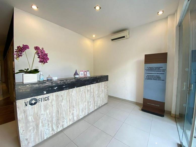 Reception area at Jl. Perserikatan A No. 01, Rawamangun with a branded desk and orchid display.