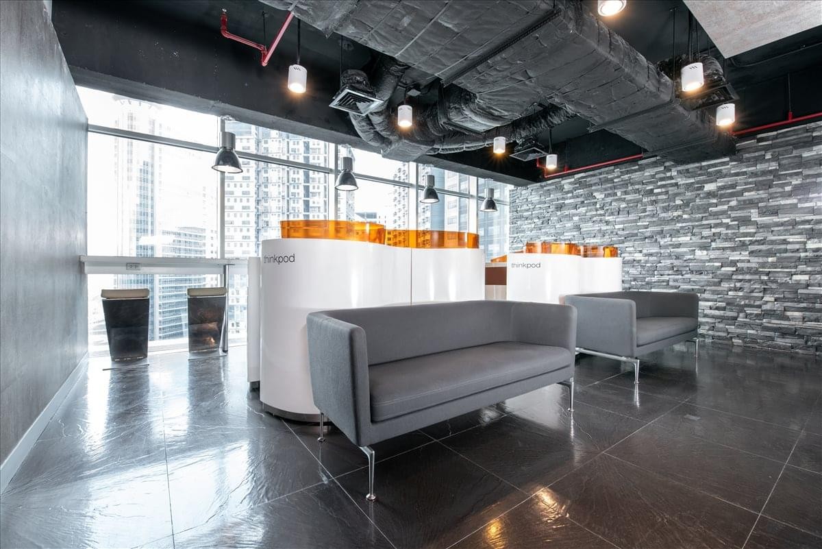 Modern communal lounge with grey sofas and a textured slate feature wall.