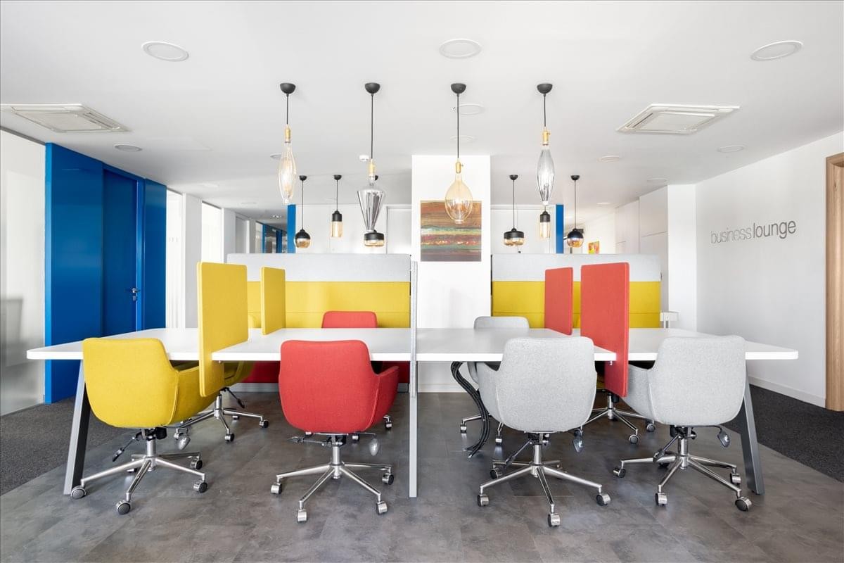 Bright communal coworking lounge with colorful chairs and designer pendant lighting.