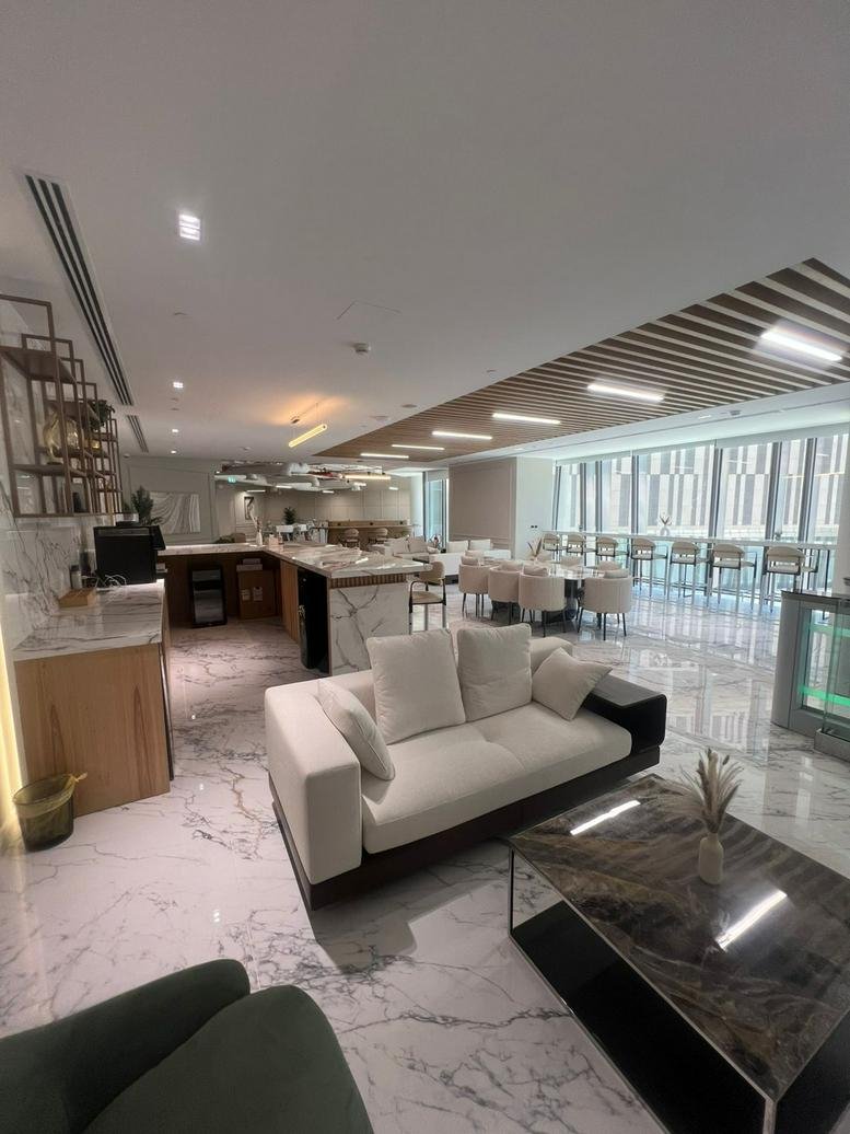 Luxe lounge area with marble floors, white sofa, and a sleek dining table in an open-plan layout.
