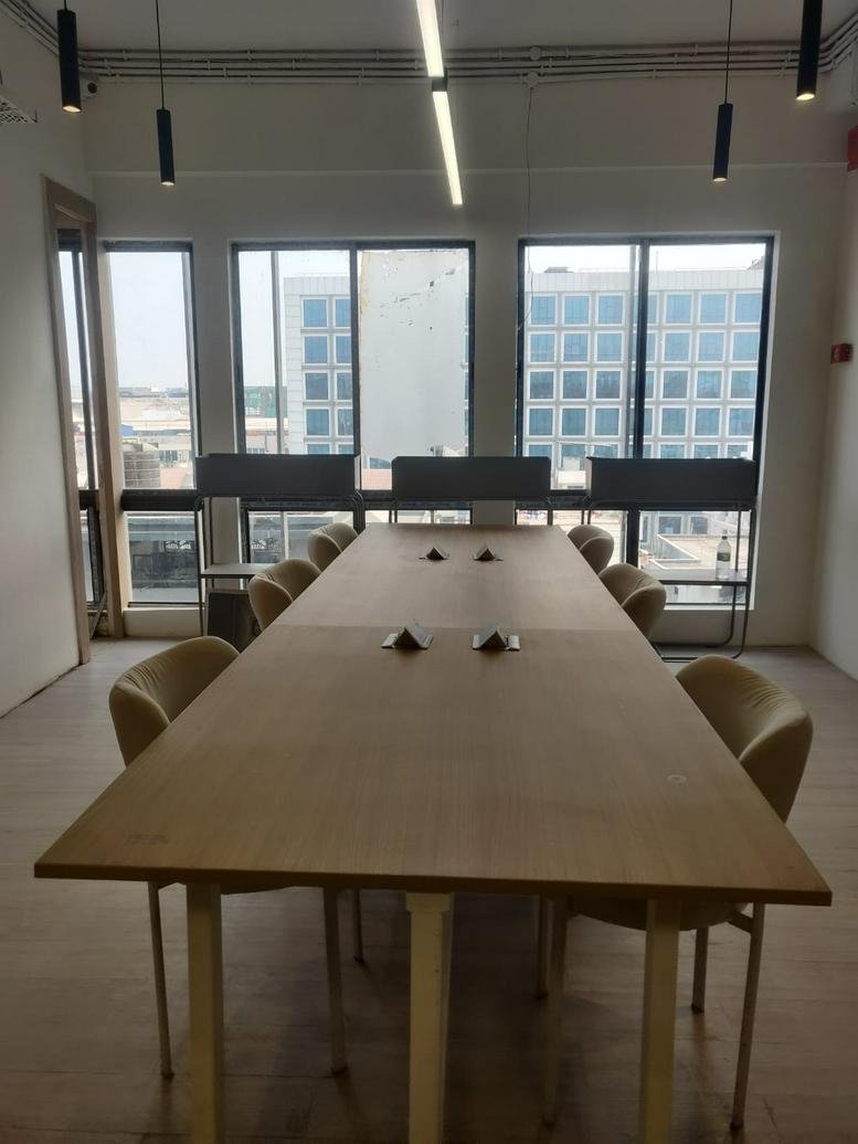 Long wooden boardroom table with tan chairs and large windows overlooking the city.